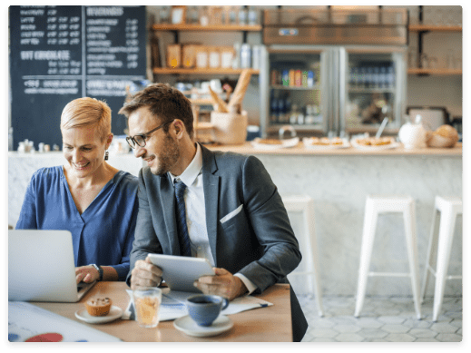 two people sitting in front of laptop at a cafe